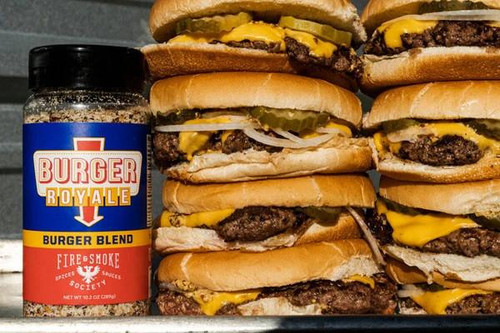 Fire & Smoke Society F&S Burger Royale Seasoning Blend 10.2 oz, a container of burger seasoning next to stacked cheeseburgers with beef patties, cheese, pickles, onions, and buns.