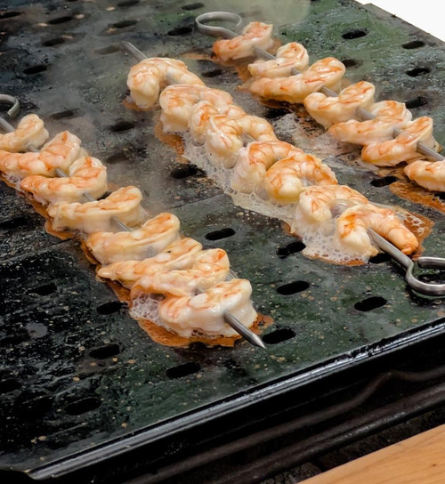 GrillGrate® for The Original & PK300 Grill, shrimp skewers grilling on a black grill grate with char marks and bubbling oil.