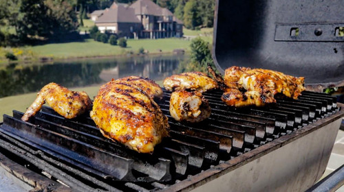 GrillGrate® for The Original & PK300 Grill, grilling chicken pieces outdoors with a scenic lake view in the background.