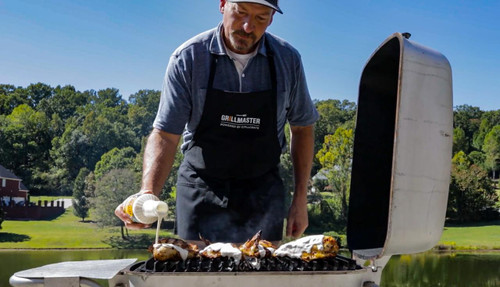 GrillGrate® for The Original & PK300 Grill, outdoor scene of a man grilling chicken on a barbeque grill with a GrillGrate insert, adding sauce to the chicken on a sunny day.