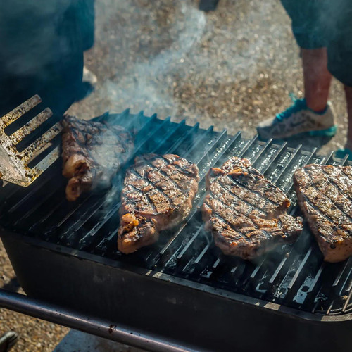 GrillGrate® for The Original & PK300 Grill, grilling steaks on a barbecue grill with visible grill marks and smoke.