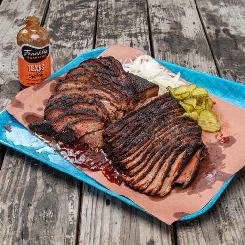 PK Grills Franklin BBQ Tray, a blue disposable food tray filled with sliced smoked brisket, pickles, onions, and BBQ sauce, placed on a rustic wooden surface.