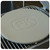 PK Grills PK Pizza Stone, round beige pizza stone with embossed PK logo, placed on grill grate.