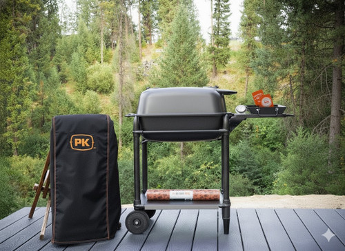 PK Grills PK300 Start Cookin' Bundle - Graphite, a portable charcoal grill with a side tray, a black carrying bag with the PK logo, set on a wooden deck outdoors surrounded by green trees.