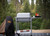 PK Grills PK300 Start Cookin' Bundle - Silver, outdoor portable grill on a wooden deck with trees in the background.