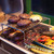 PK Grills PK300 Start Cookin' Bundle - Silver, barbecue grilling with hamburger patties and grilled vegetables on a stainless steel grill rack.