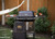 PK Grills PK300AF Start Cookin' Bundle - Coal, outdoor charcoal grill with side shelves, cooking accessories, and a carrying bag, set up in a backyard garden.