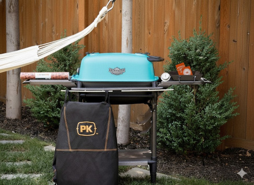 PK Grills PK300AF Start Cookin' Bundle - Teal, outdoor barbecue grill with teal lid, side tray with accessories, black backpack, and a hammock in the background.