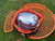 PK Grills PKGO Carrying Bag, portable grill stored inside a black and orange carrying bag on a green grassy surface.