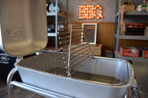 PK Grills Stainless Steel Cooking Grid & Charcoal Grate for Original PK, showcasing a stainless steel cooking grid and charcoal grate inside an open grill, with a cozy background featuring a decorated BBQ sign.