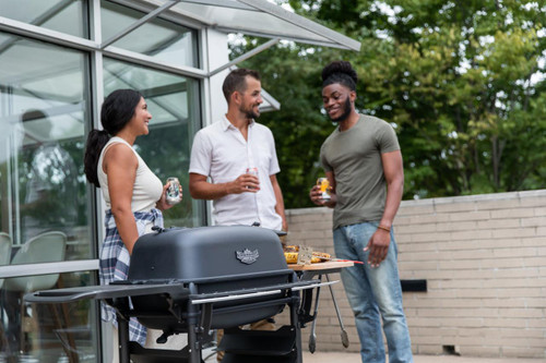 PK Grills The All New Original PK300AF Grill & Smoker - Coal, outdoor scene with three people enjoying food and drinks around a grill.