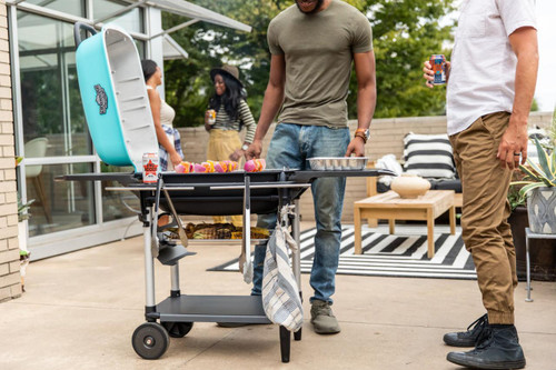 PK Grills The All New Original PK300AF Grill & Smoker - Teal, outdoor scene with people grilling and socializing on a patio.