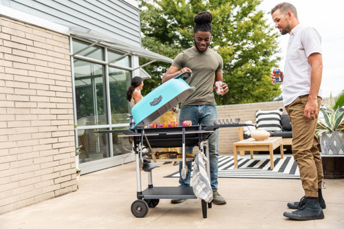 PK Grills The All New Original PK300AF Grill & Smoker - Teal, outdoor grilling scene with friends enjoying a barbecue on patio.