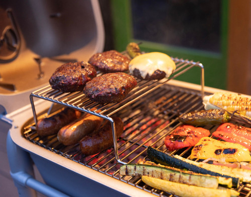 PK Grills The Littlemore Grid for PK Grills, metal grilling rack with burger patties, sausages, and vegetables on a barbecue grill.