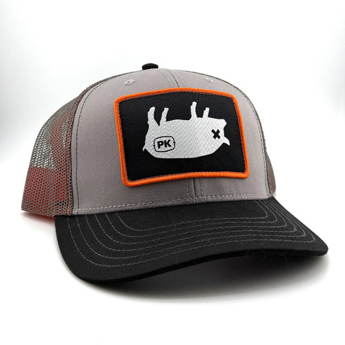 PK Pig Hat Ash Grey, adjustable trucker cap with a black brim, grey front panels, and a mesh back, featuring a white pig patch with black outlines and orange border.