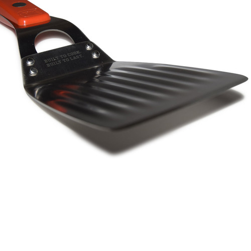 The Stainless Steel PK Spatula, a sleek black kitchen tool with a sturdy handle and wide slotted surface for flipping and serving food.